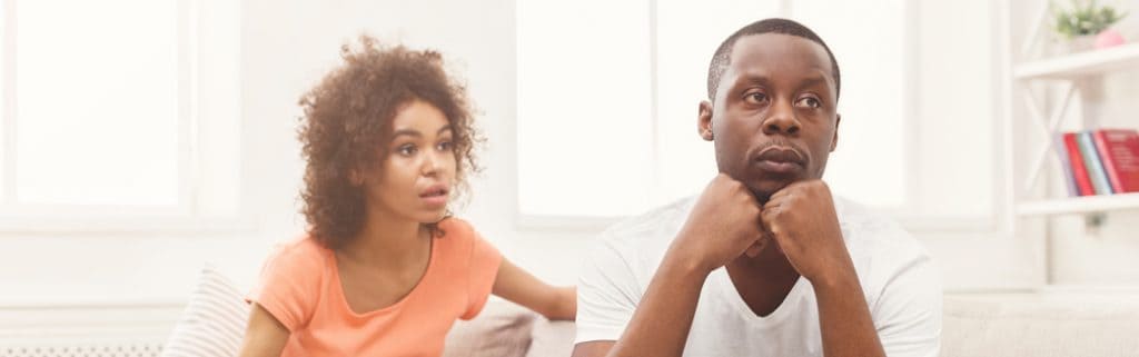 man and woman sitting on the couch looking troubled